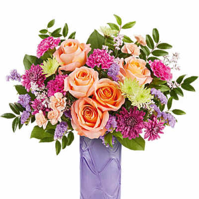 Peach roses and pink flowers in a purple glass vase