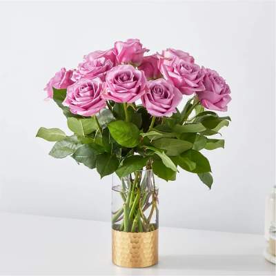 Pink roses arranged in a clear glass vase with a gold base