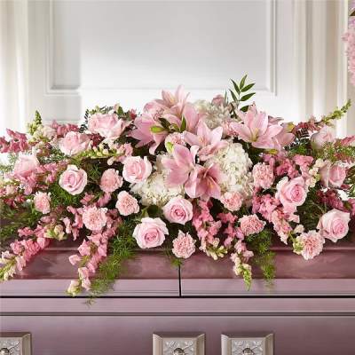 Pink and white floral arrangement with roses and lilies on a casket