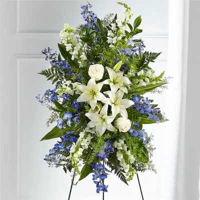 Standing floral spray with white lilies, white roses, and blue flowers