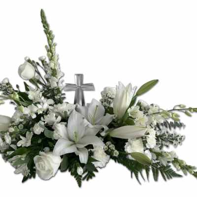 Low white floral spray with lilies, roses, and a central silver cross accent