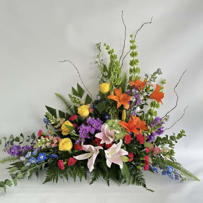 Large mixed floral arrangement with lilies, roses, and bright accent flowers