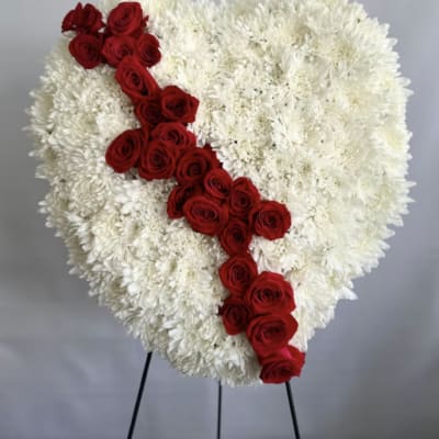 Heart-shaped standing arrangement of white flowers with a diagonal stripe of red roses.
