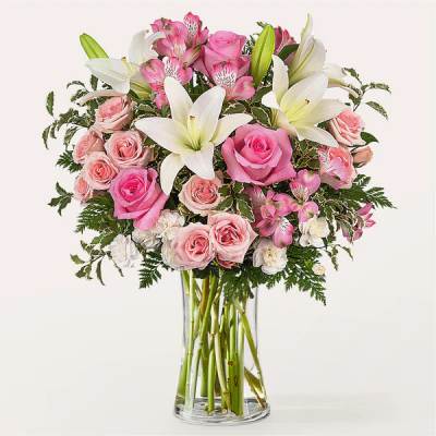 Pink roses and white lilies arranged in a clear glass vase