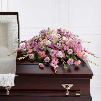 Pink and lavender floral spray on a dark wood casket