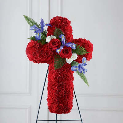 Red floral cross on a black stand with roses and blue flowers