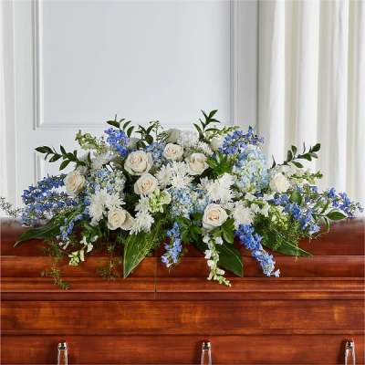 White and blue floral arrangement on a wooden casket