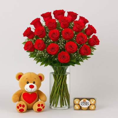 Red roses in a glass vase with a teddy bear and chocolates