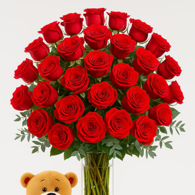 Bouquet of red roses in a clear glass vase with a teddy bear holding a heart