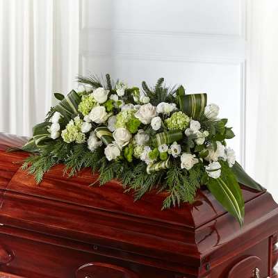 White and green floral spray on a polished casket