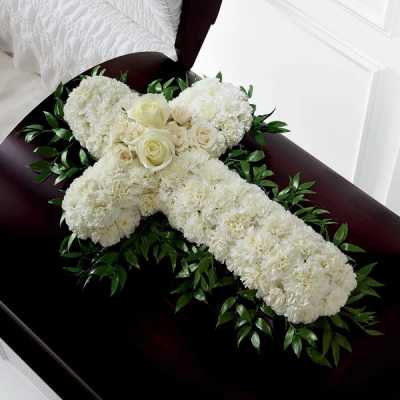 White floral cross arrangement on a dark casket