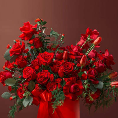 Red rose arrangement in a red hatbox with ribbon