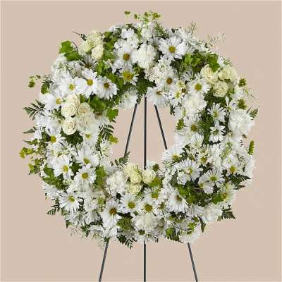 White floral wreath on a black easel stand