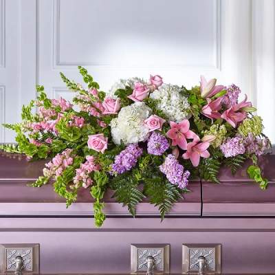 Pink and white floral casket spray with lilies, roses, and hydrangeas