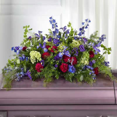 Casket spray with blue, purple, and pink flowers