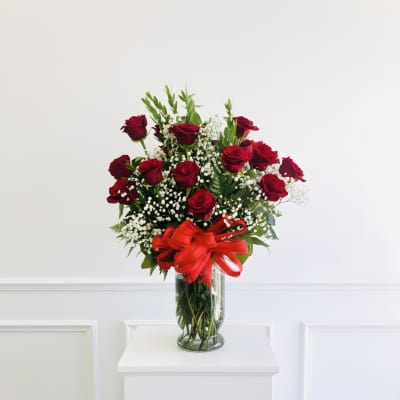 Red roses in a clear glass vase with a red ribbon bow