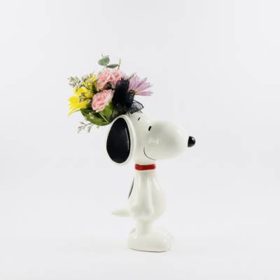 Snoopy figurine holding a small bouquet of pink and yellow flowers