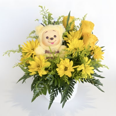 Yellow flower arrangement with a plush bear in a white vase