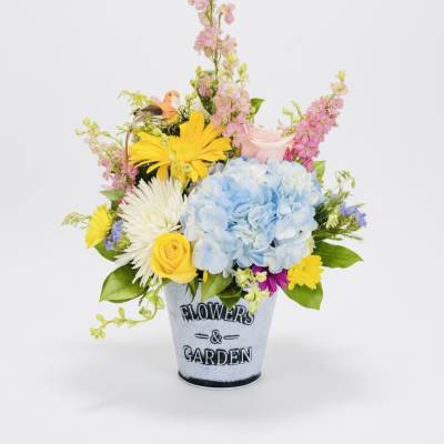 Mixed bouquet in a metal pot with blue hydrangea, roses, and daisies