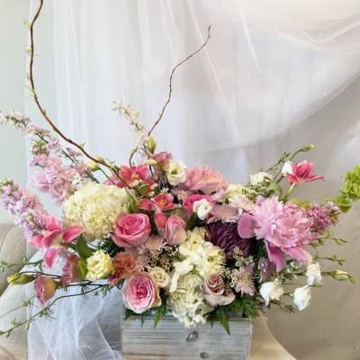 Pink and white floral arrangement in a wooden box with tall branches