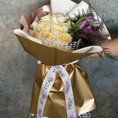 Bouquet of cream roses and purple tulips wrapped in gold paper