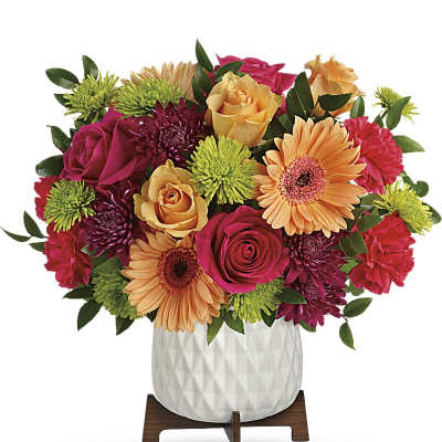 Bright mixed bouquet in a white vase on a wooden stand