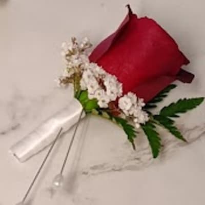 Red rose boutonniere with white filler flowers and green fern leaves