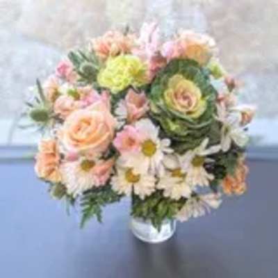 Round bouquet of peach roses, white daisies, and green ornamental blooms in a glass vase