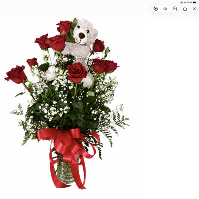 Red roses arranged with a teddy bear in a glass vase
