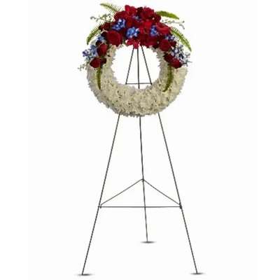 Standing funeral wreath with red, white, and blue flowers on a metal easel