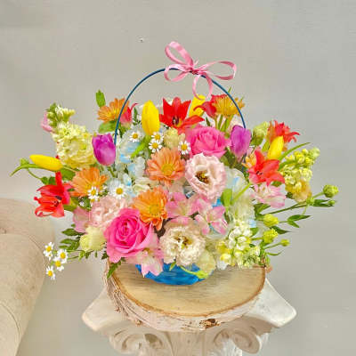 Colorful mixed flower basket with a pink ribbon handle