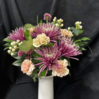 Pink chrysanthemums and peach carnations in a white vase