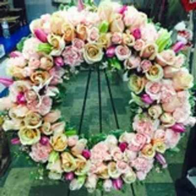 Heart-shaped floral wreath with pink and cream roses on a stand
