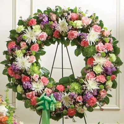 Large floral wreath with pink roses and white star-shaped blooms on a stand