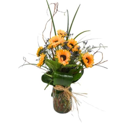 Orange sunflowers in a glass vase with tall grass accents