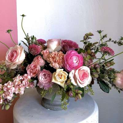 Pink and cream rose arrangement in a gray vase