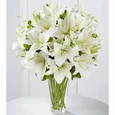 Tall arrangement of white lilies in a clear glass vase