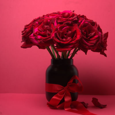 Red roses in a black vase with a red ribbon