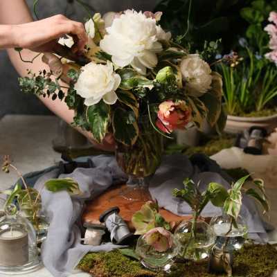 White and blush floral arrangement in a glass vase with small glass bud vases nearby
