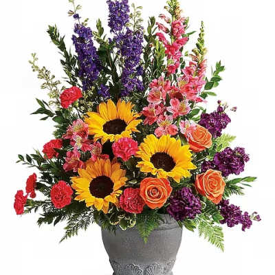 Mixed bouquet with sunflowers, roses, carnations, and purple spikes in a gray vase
