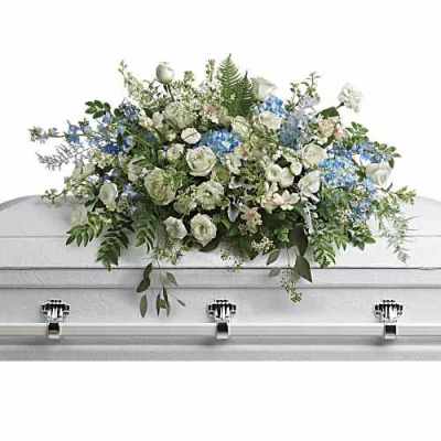 White and blue floral casket spray on a white casket