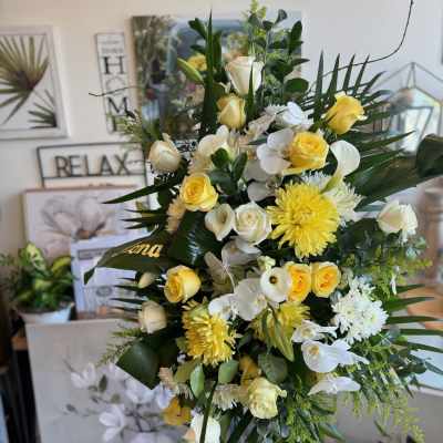 Tall floral spray with yellow and white roses and orchids