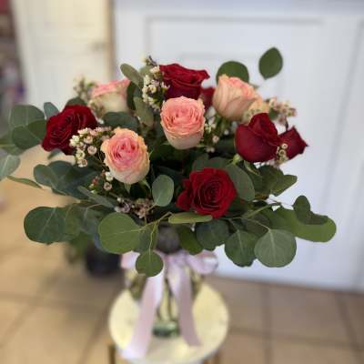 Bouquet of red and blush roses with greenery in a glass vase
