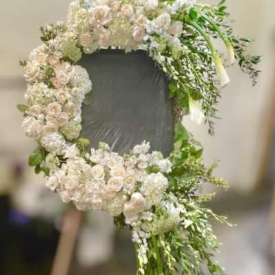 Large floral wreath of pale roses and white blooms on a stand