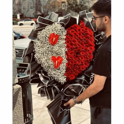 Heart-shaped bouquet of red roses and white baby's breath with black ribbon trim