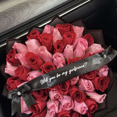 Bouquet of red and pink roses with a black ribbon reading "Will you be my girlfriend?"