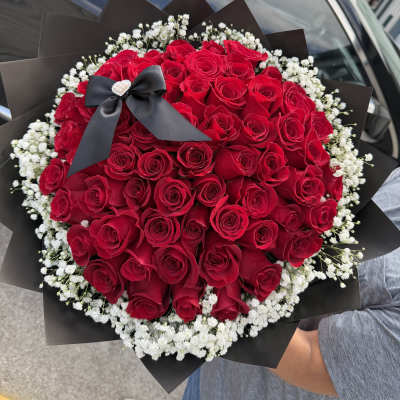 Large bouquet of red roses with white baby's breath and a black ribbon