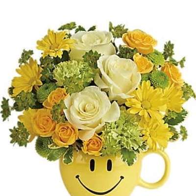 Yellow and white flower arrangement in a yellow smiley-face mug
