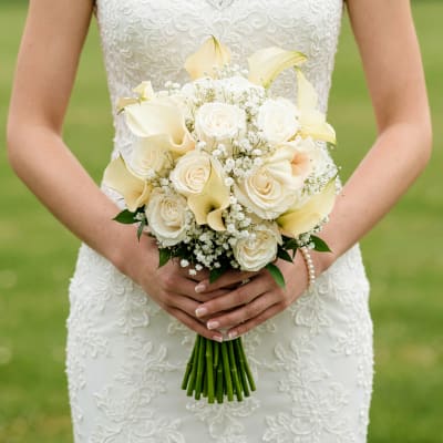 Bride holding a white bouquet with roses and calla lilies