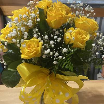 Yellow rose bouquet with baby's breath in a glass vase and yellow ribbon